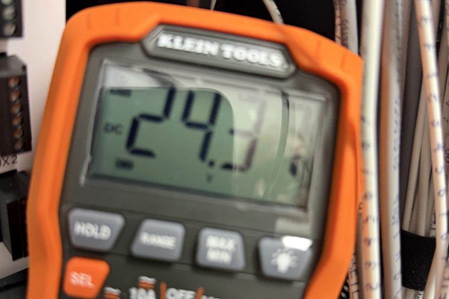 Multimeter measuring DC supply voltage at the access control panel during commissioning