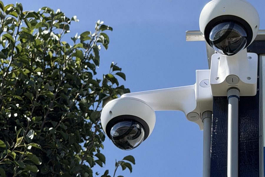 Two Verkada outdoor dome cameras on a single pole mount covering a yard approach