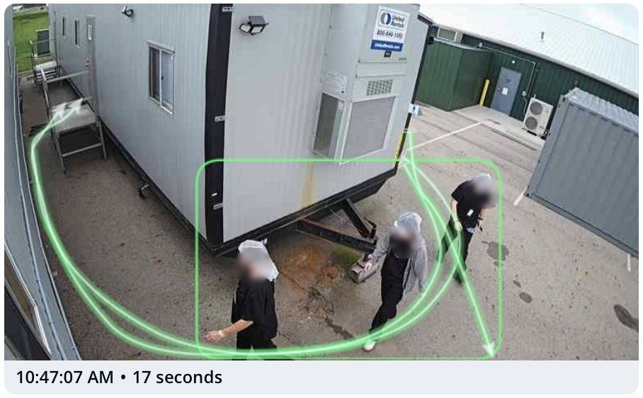 Camera view beside a processing trailer with motion trails around three workers